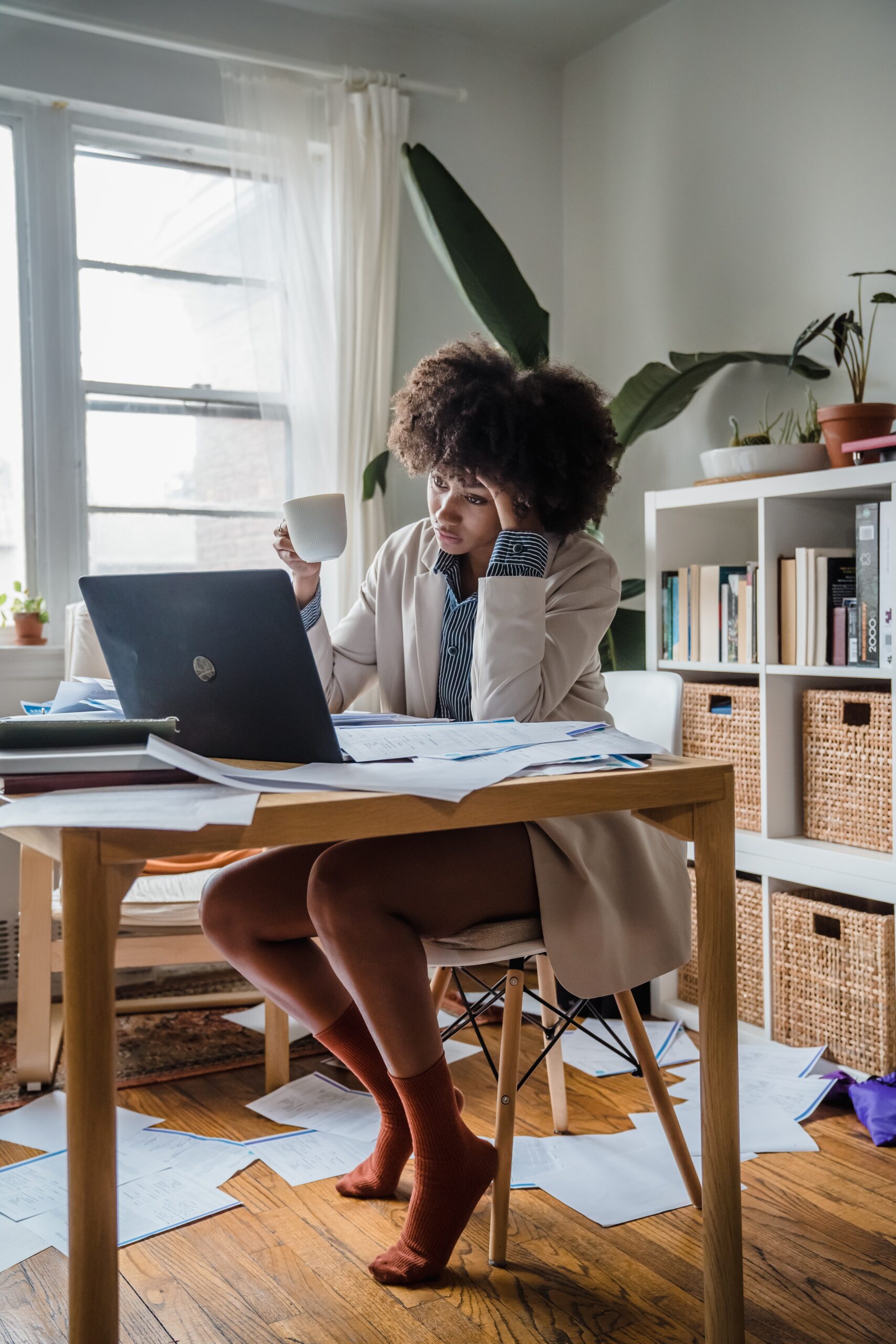 A woman who is struggling at her desk looking overwhelmed in front of her computer.