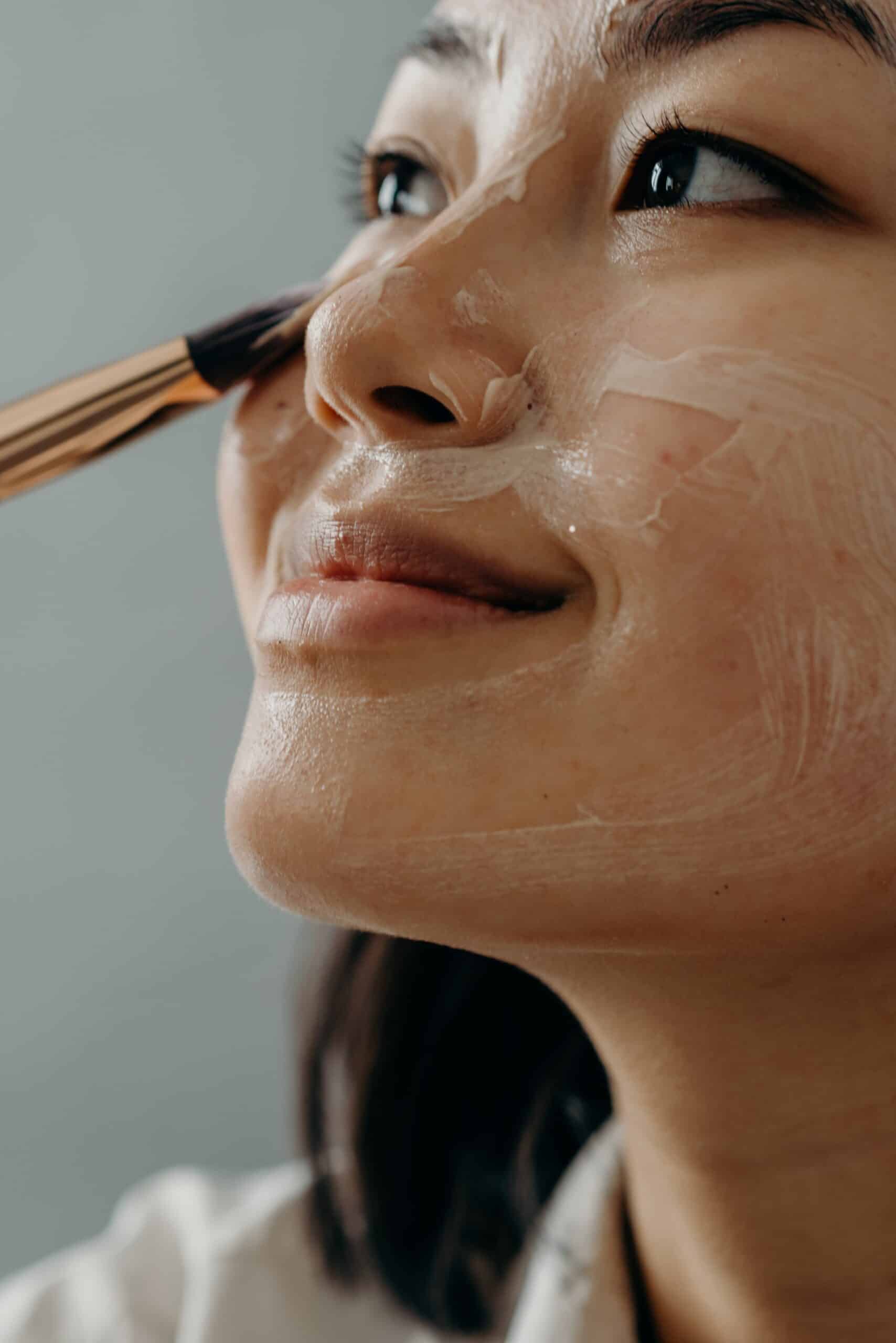 Asian woman applying skincare mask on her face