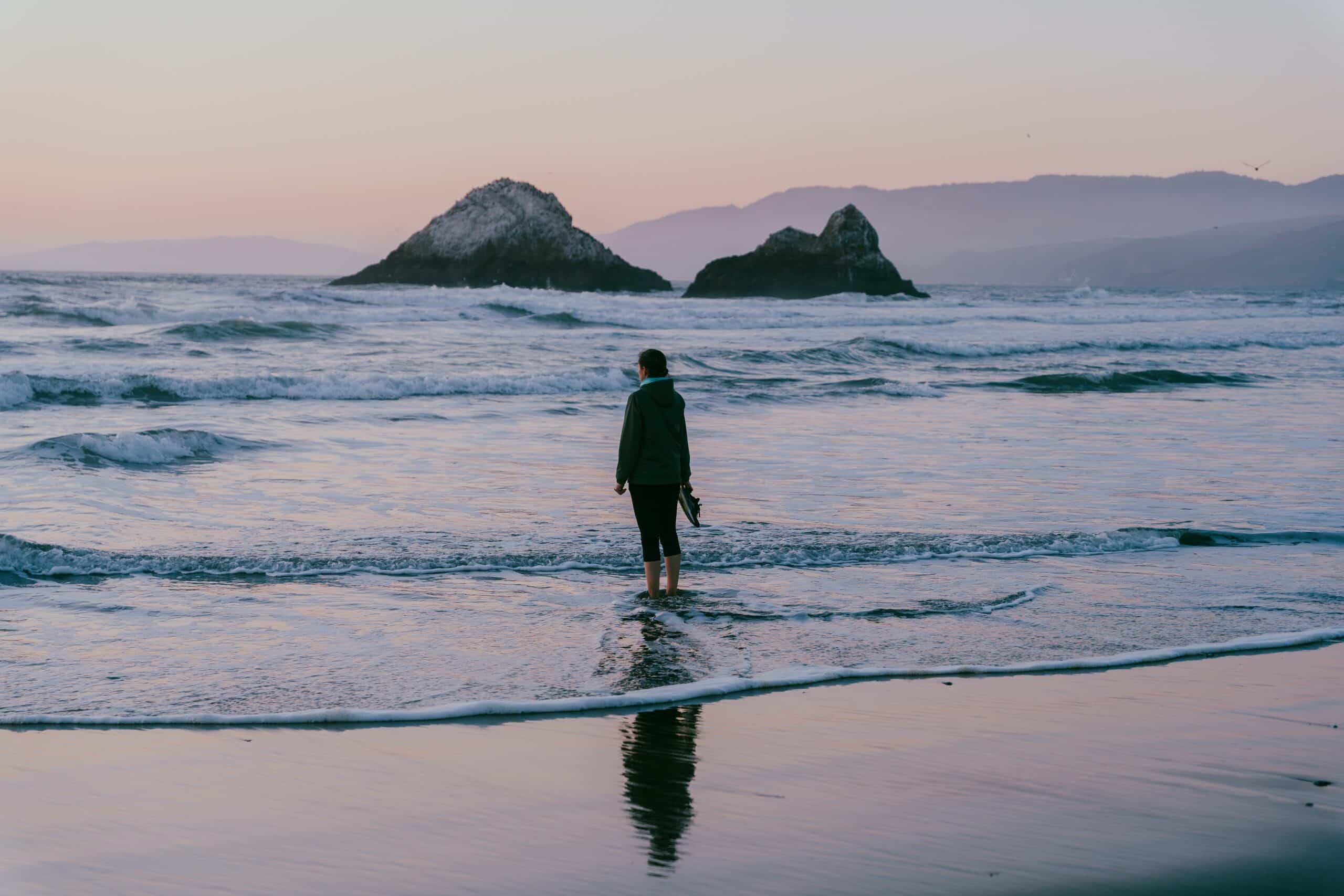 Woman standing in the ocean and looking out into the horizon.