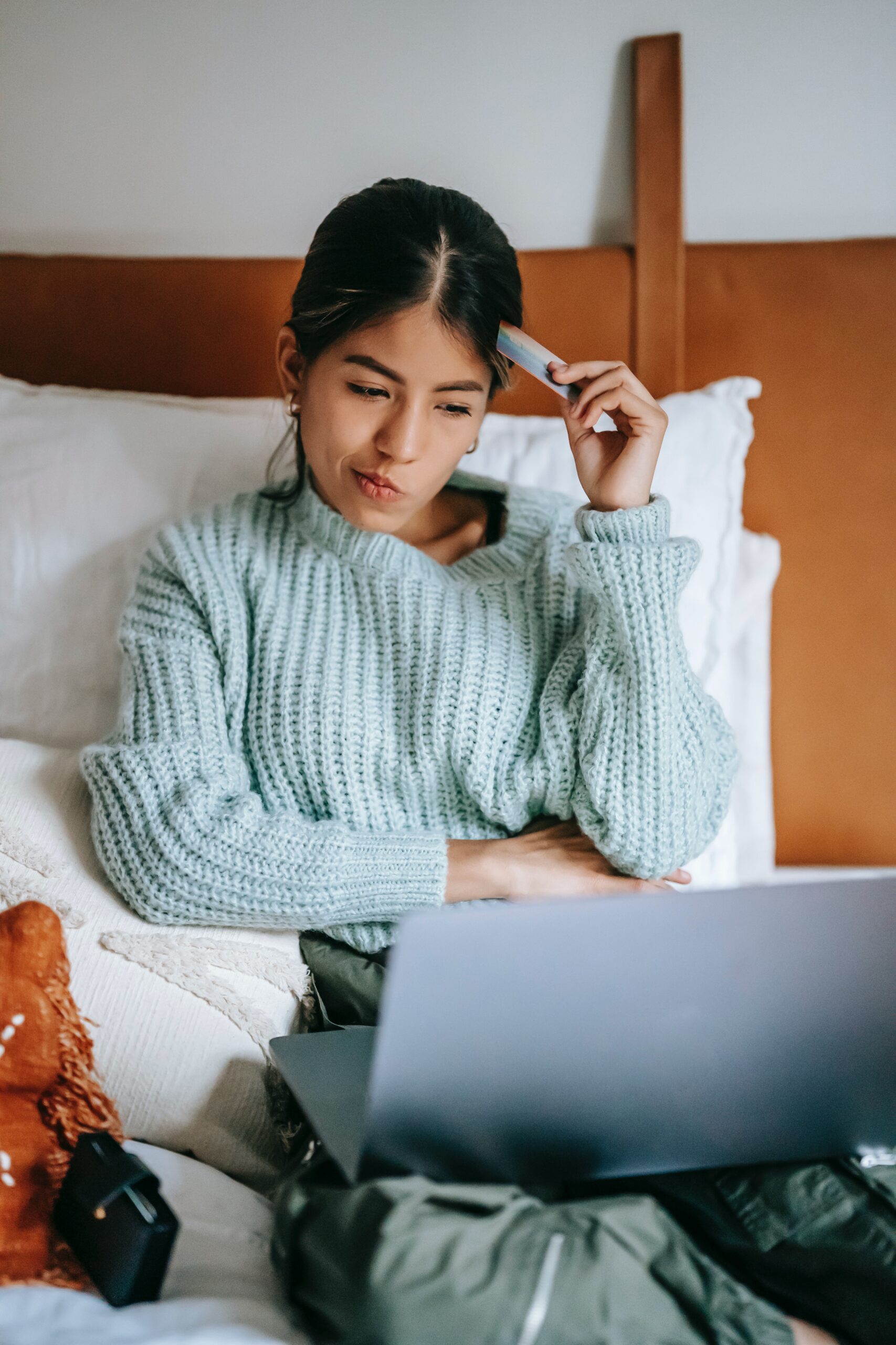 A young woman is looking down at her laptop trying to figure out her finances.