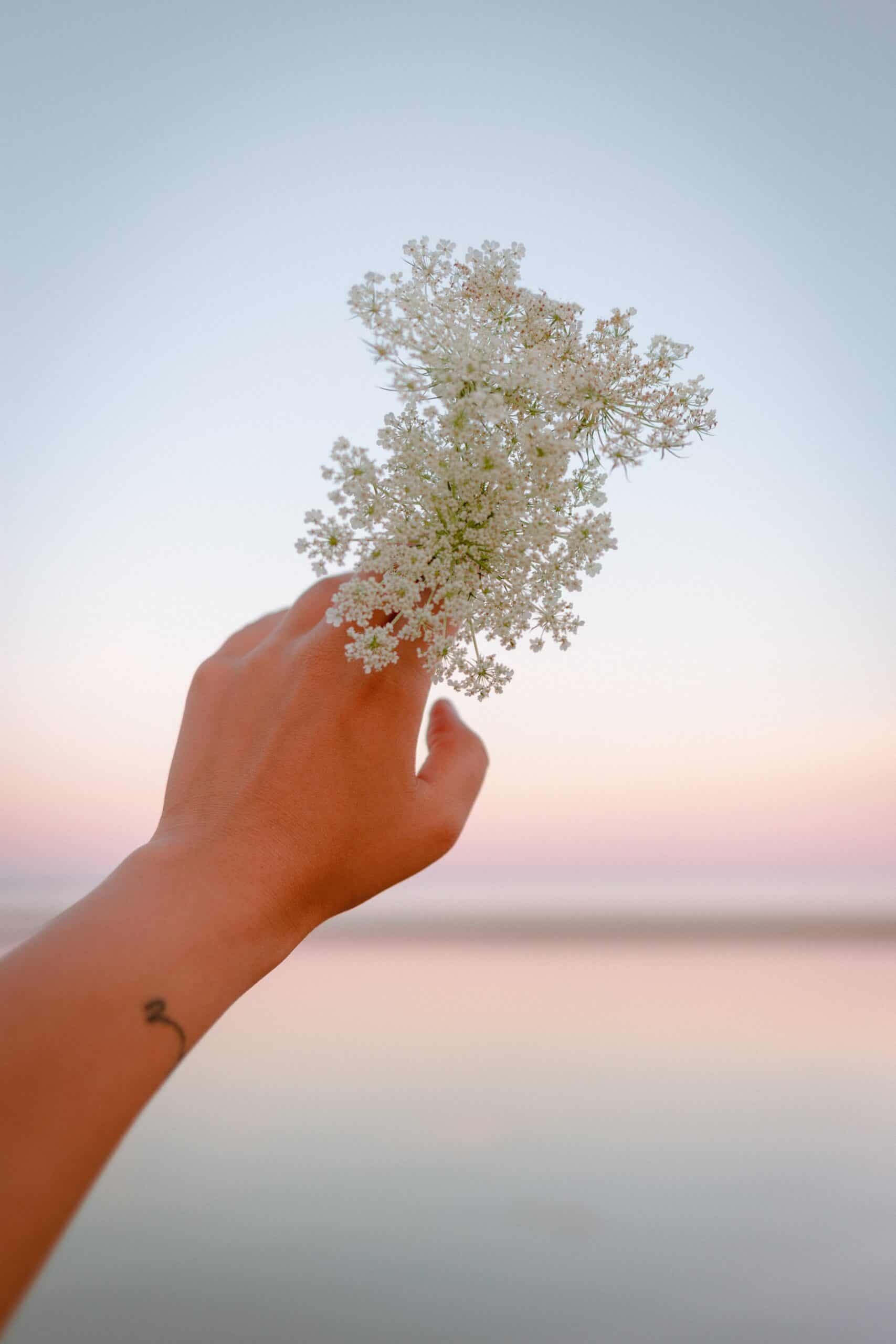 A woman holding up flowers to the sky. Learn how to get into touch with yourself